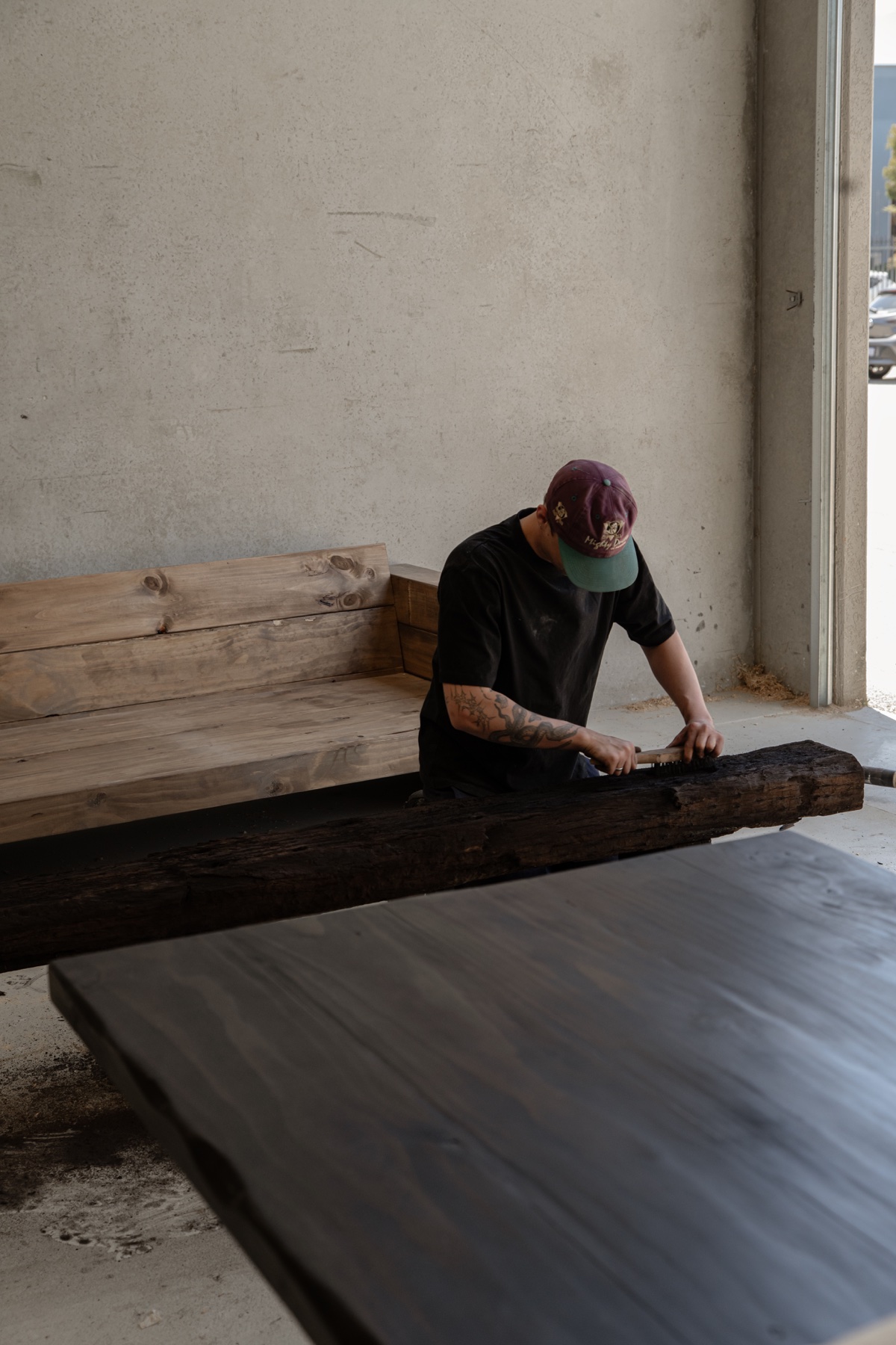 A furniture maker working a timber beam by hand in the workshop